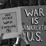 hands holding up signs saying No More War Funding and War is Bankrupting U.S.