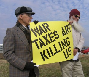 Don and Peter holding a yellow sign saying in black letters, WAR TAXE$ ARE KILLING US.