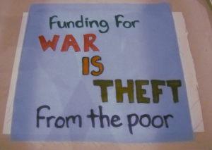 fabric square with text "funding for WAR IS THEFT from the poor"