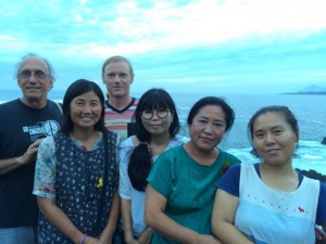 Six people posing for a picture in front of the ocean.