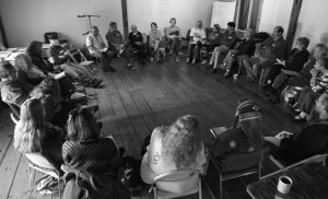 30 people sitting on folding chairs in a circle