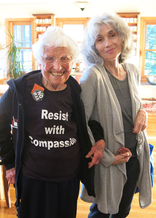 Frances Crowe wearing a shirt that says Resist with Compassion, links arms with Susan Lannen