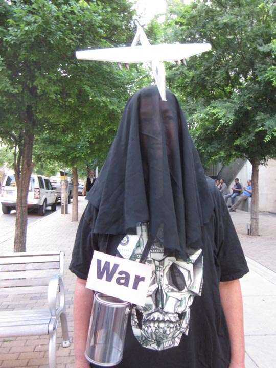 Person shrouded in black with death-mask shirt, labeled “War”