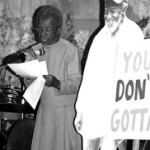 Juanita speaking next to an image of her partner Wally with a sign saying "You Don't Gotta"