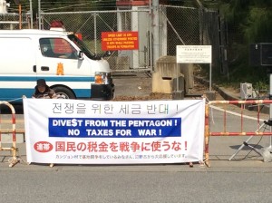 Jason Rawn posted this picture on Facebook of a banner created in February 2016 during his stay in Japan. It reads in English, "Dive$t from the Pentagon! No Taxes for War!" and variations on "No Taxes for War!" in Japanese and Korean.