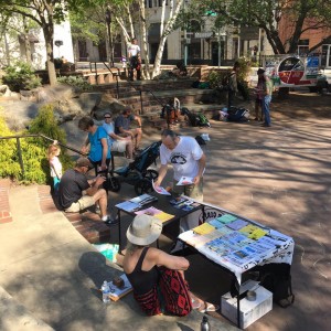 people mill about a literature table in a public plaza