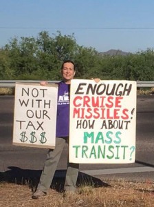 woman holding signs reading “not with our tax dollars” and “enough cruise missiles! how about mass transit?”