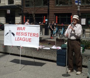Brad Lyttle at the microphone with a War Resisters League sign nearby