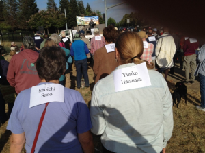 Two people attending the rally wearing a piece of paper on their backs with the names of victims of the atomic bombings: Shoichi Sano and Yuriko Hatanaka. Other people in front of them are also wearing papers on their backs with victims' names printed on them.