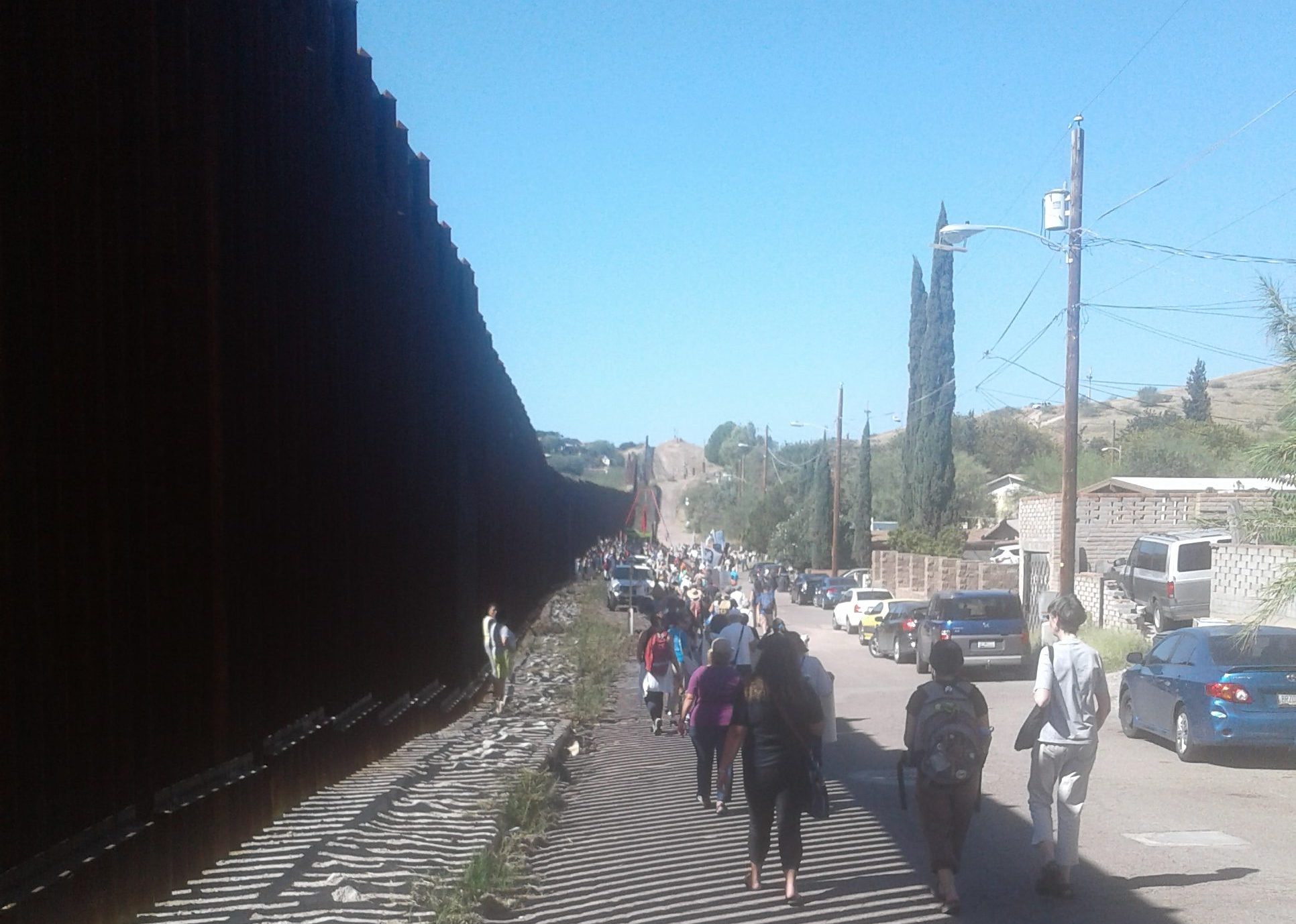 border fence stretches into the distance on the left, as SOAW border convergence attendees march alongside it