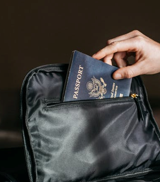 a hand sliding a US passport into a pocket of a black bag