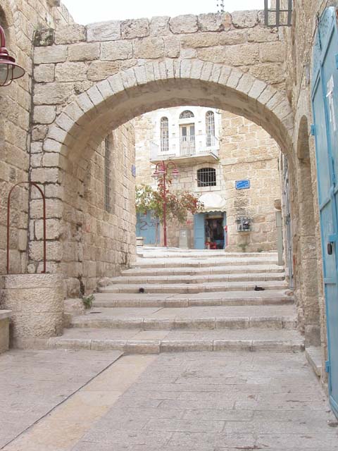 a stone arch over a paved lane in Beit Sahour, with a stone building in the background