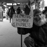 Man holding a sign reading"Seeking Human Kindness "
