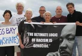 7 activists holding a banner that states "the ultimate logic of racism is genocide"