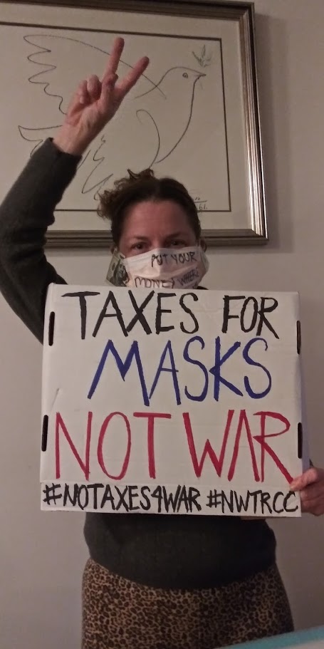 woman holds sign and shares peace sign