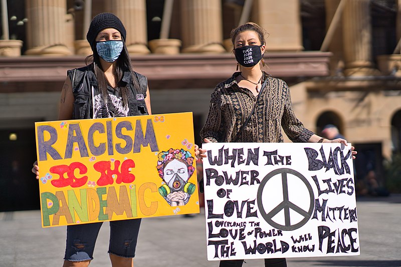 two people holding signs and wearing masks