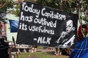 black banner held outside that reads 'Today capitalism has outlived its usefulness'