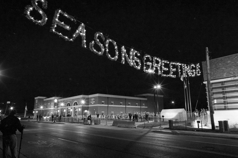seasons greetings in lights above a street with Ferguson police officers in background