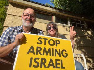 Paul and Kima holding a sign that states, "Stop Arming Israel."